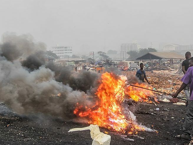 A metal scrap worker burning insulated copper wires to collect copper in Ghana. Credit: Muntaka Chasant/ Wikimedia Commons.
